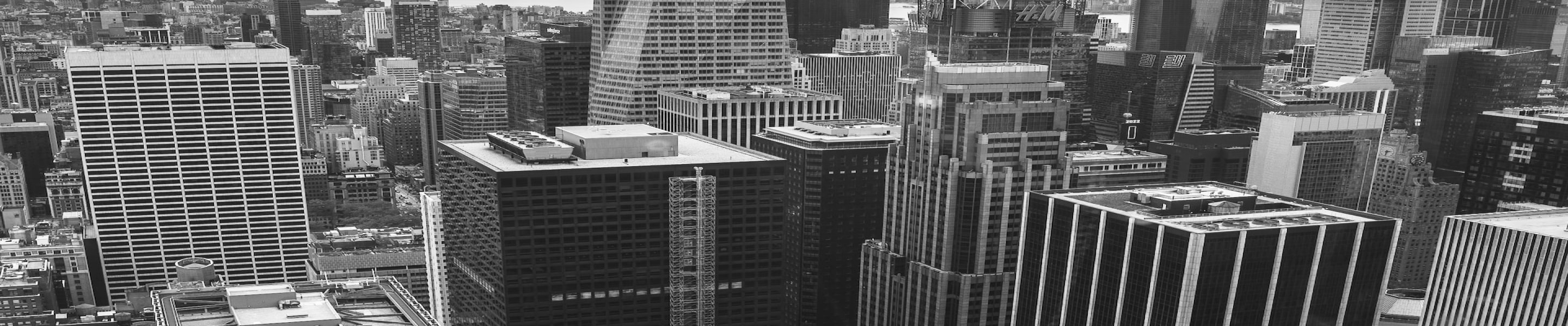 ニューヨークの高層ビル街と一方通行標識、信号機が写るモノクロ写真。